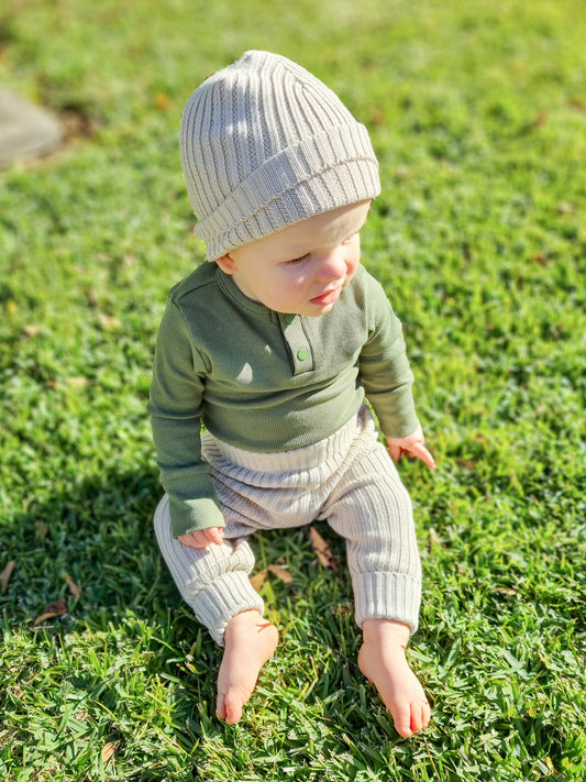 Olive long sleeve bodysuit in organic stretch rib, paired with rib knit leggings & beanie in oat colour.