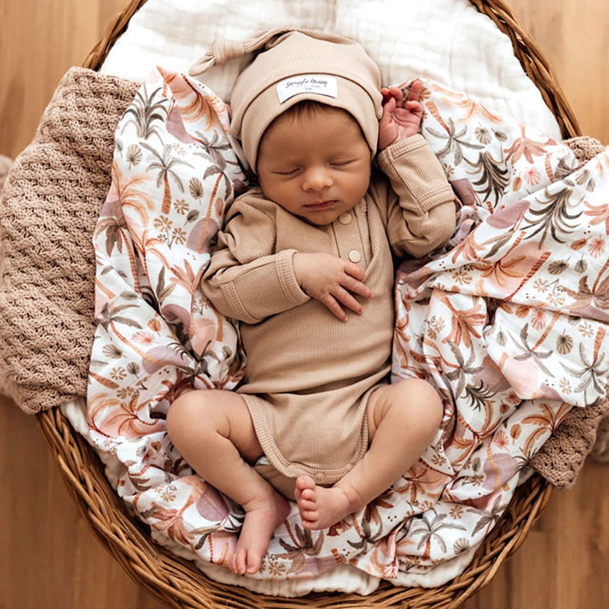 Newborn baby in the Snuggle Honey long sleeve bodysuit in natural Pebble colour. In a stretch rib fabric.