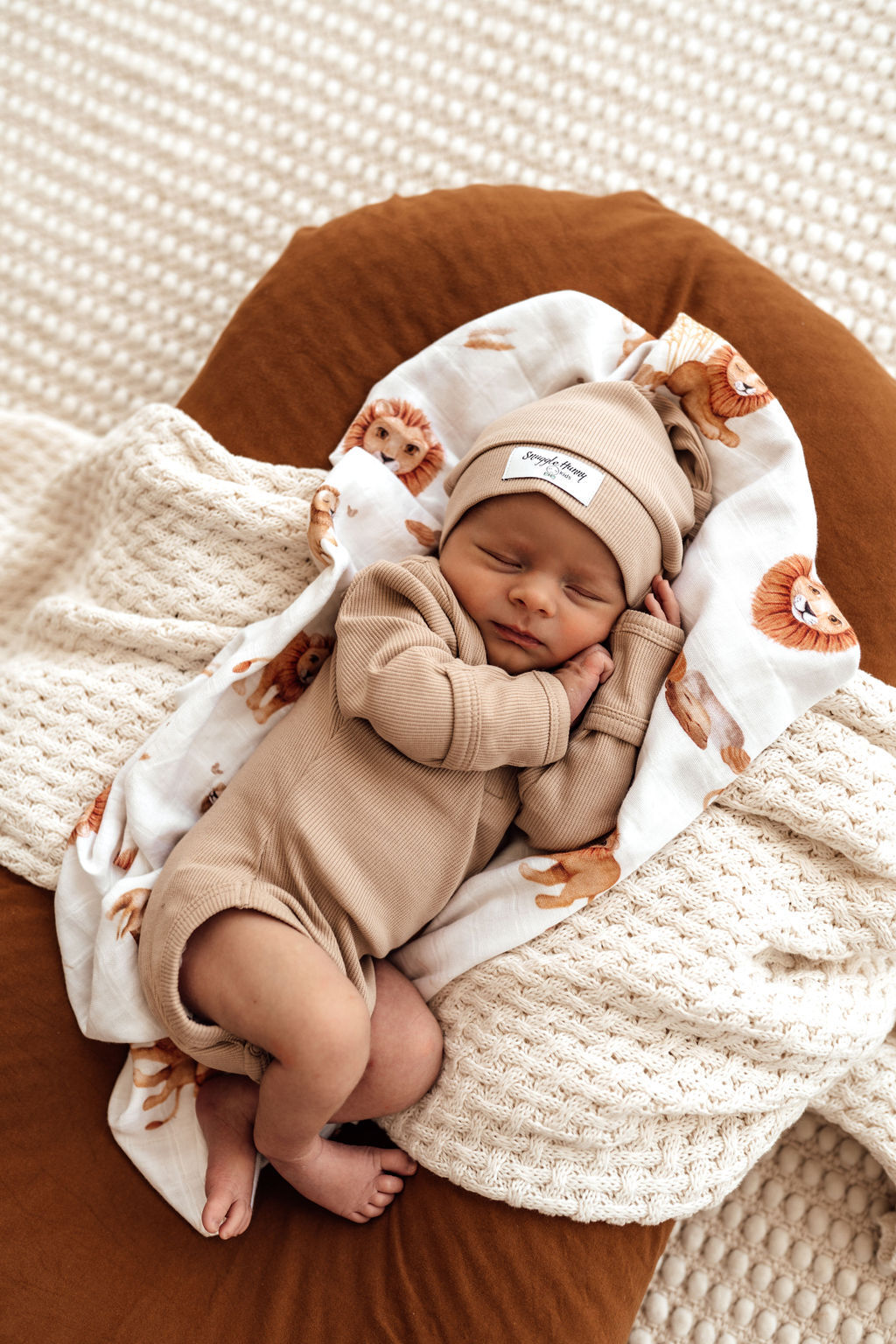 Newborn baby in the Snuggle Honey long sleeve bodysuit in natural Pebble colour. In a stretch rib fabric.