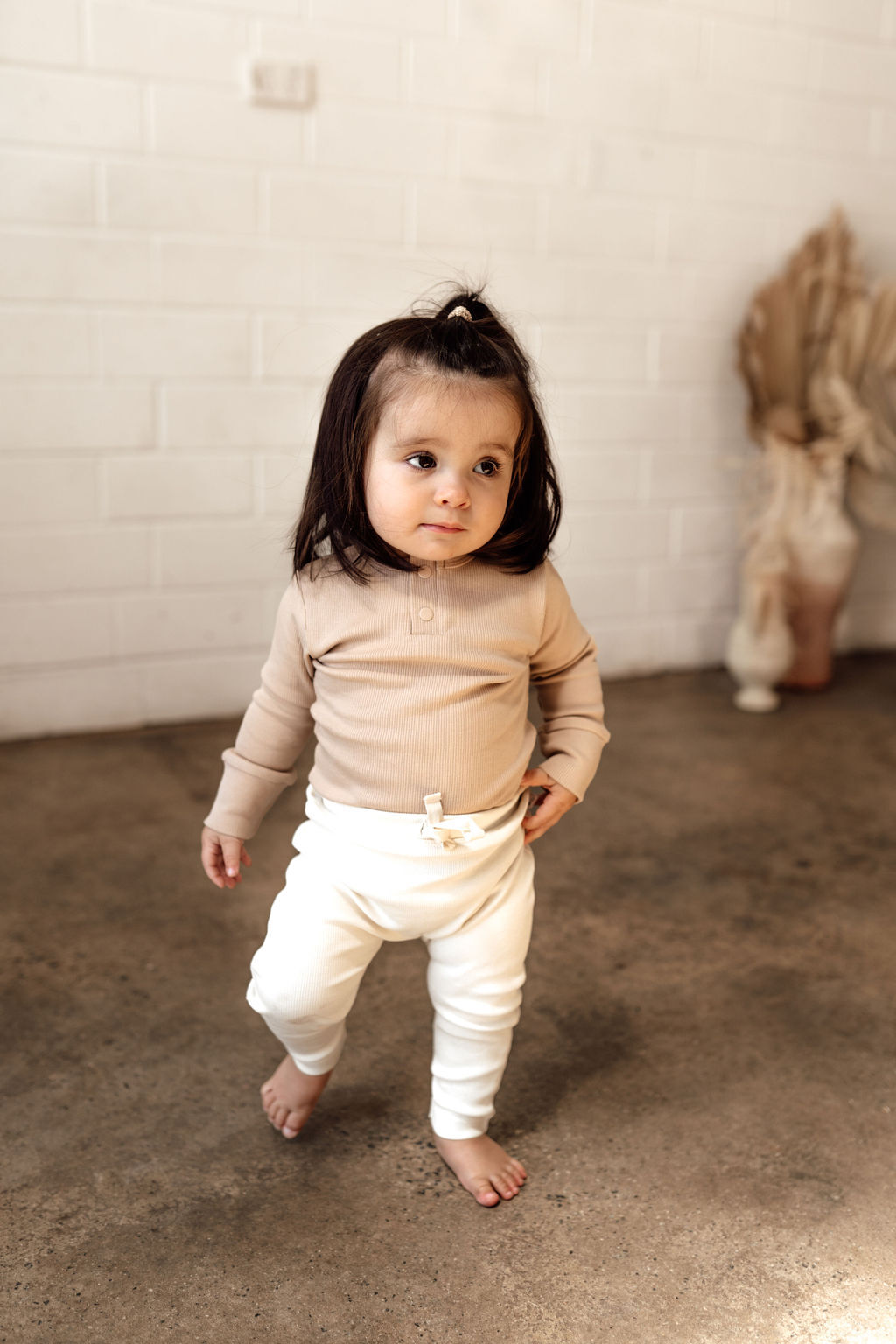 Toddler in the Pebble long sleeve bodysuit, paired with gorgeous rib pants in the Halo (cream) colour.