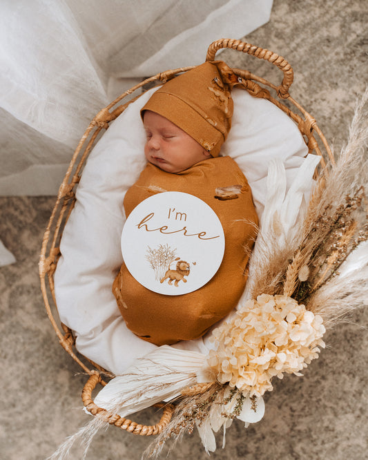 newborn swaddled in the Roar jersey wrap & beanie set withthe "I'm here" milestone card 