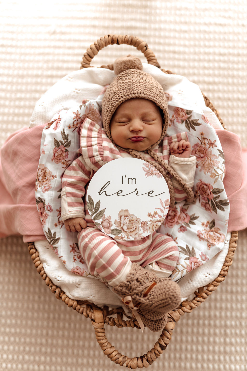 Newborn dressed in the rose stripe growsuit, with the Rose milestone card 'I'm here'.